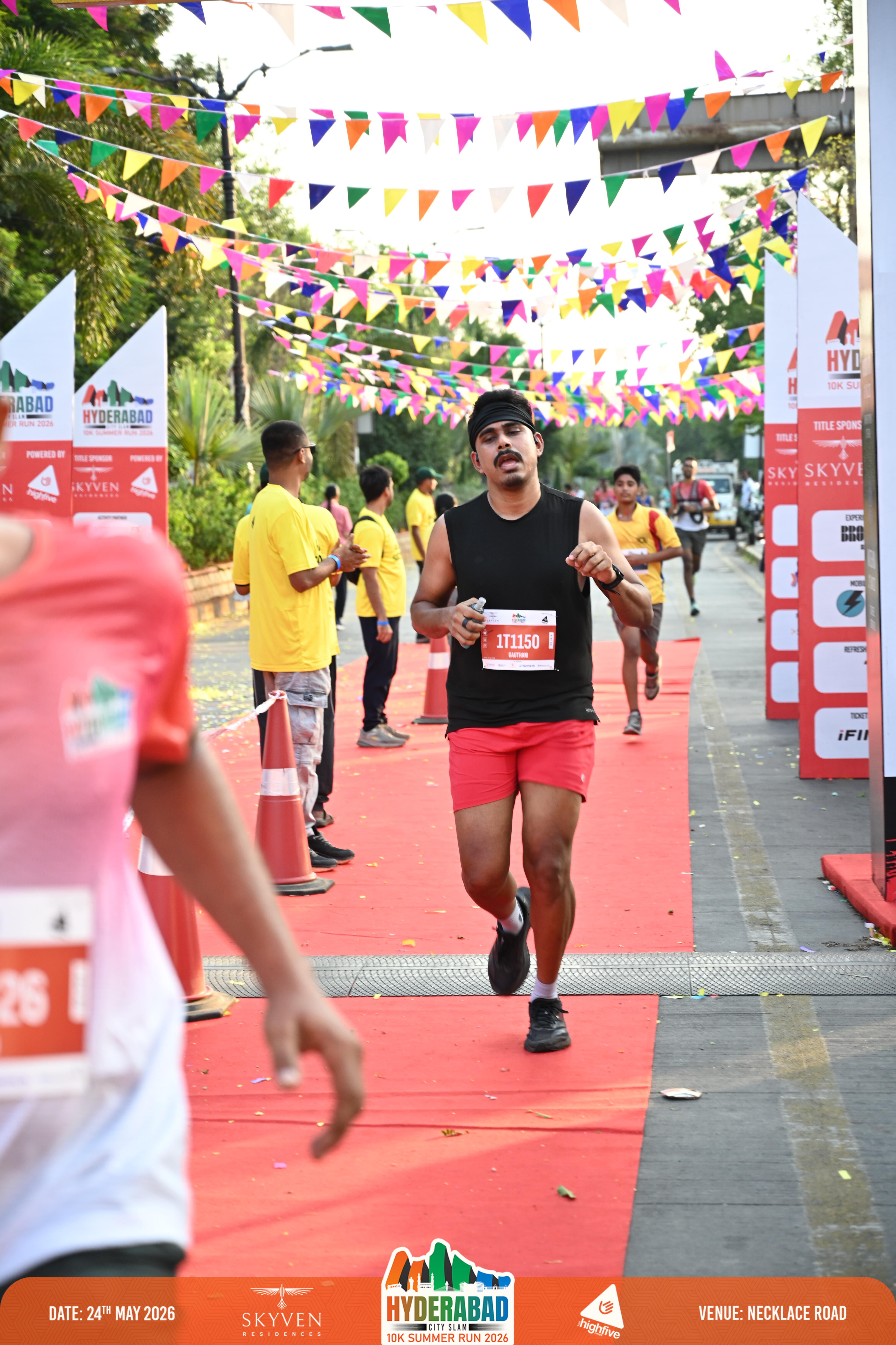 Finish line — black tank, bib 1T1150. Look at the hands, the shoulders, and where the arms are sitting.